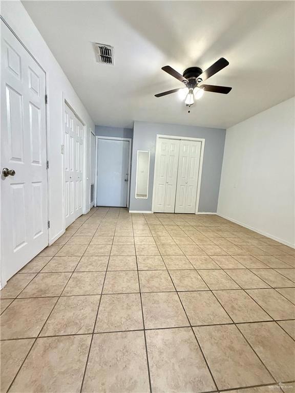 Unfurnished bedroom featuring two closets, light tile patterned floors, and ceiling fan