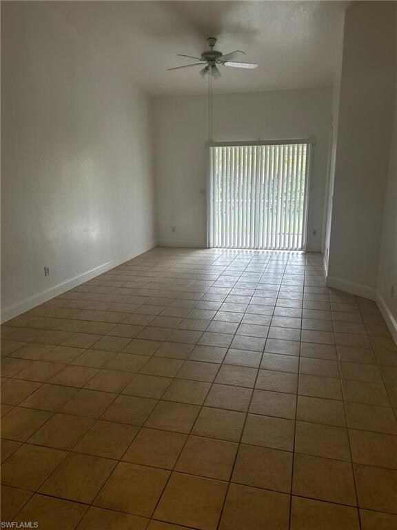 Spare room with a ceiling fan, light tile patterned floors, and baseboards