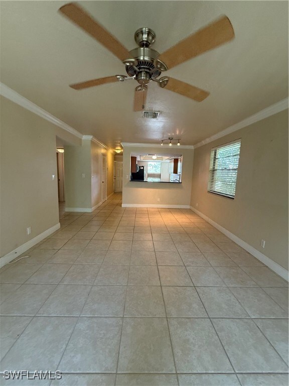 Unfurnished room with ornamental molding, light tile patterned flooring, and ceiling fan