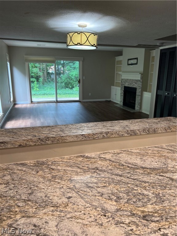 Unfurnished living room with a high end fireplace, built in features, a textured ceiling, and hardwood / wood-style floors