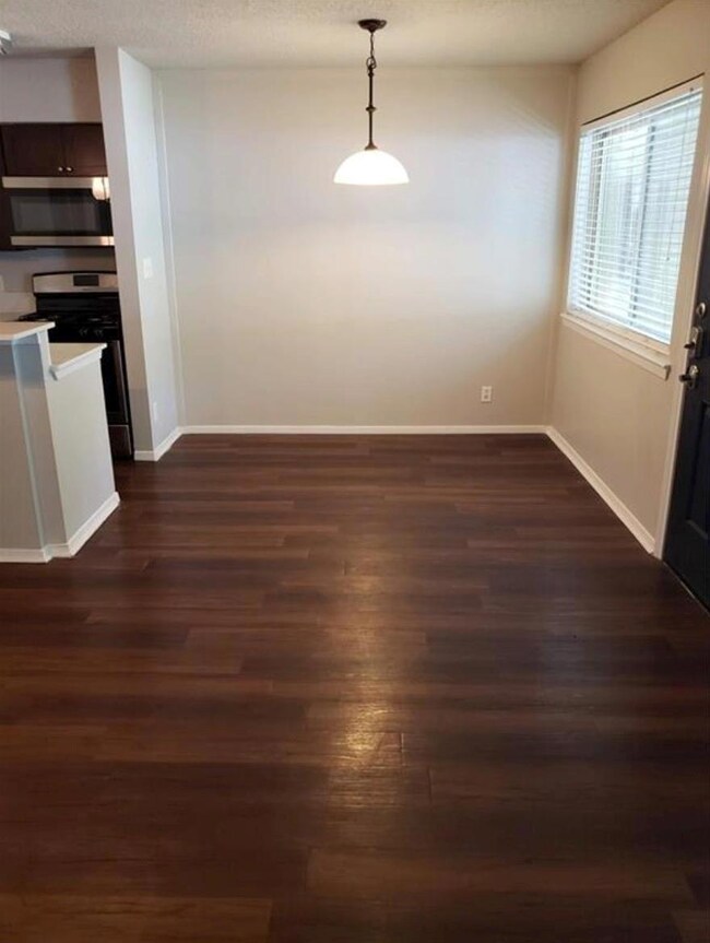 Unfurnished dining area with dark wood finished floors and a textured ceiling