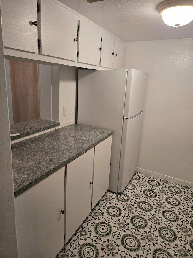 This kitchen features white cabinetry with ample s