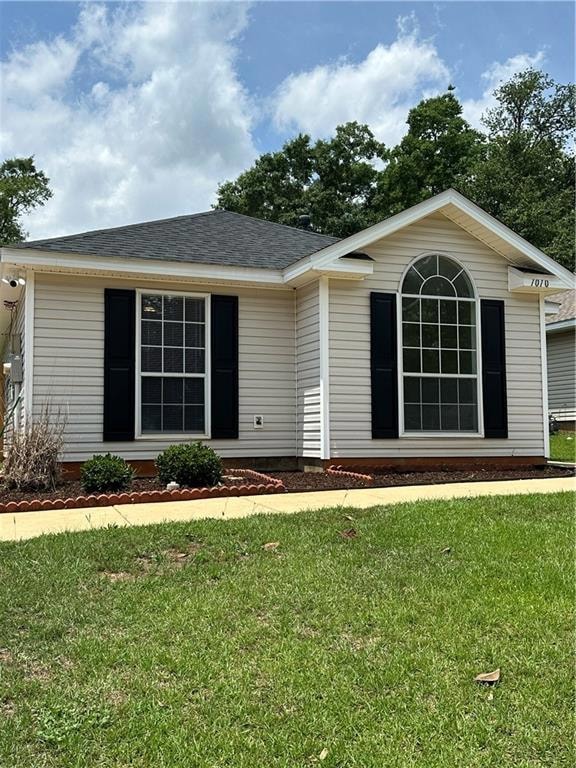 Ranch-style home featuring a front yard and a shingled roof