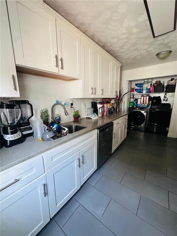 Kitchen featuring dishwashing machine, washer / dryer, white cabinetry, a textured ceiling, and decorative backsplash