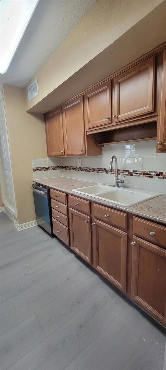 Kitchen with light wood-type flooring, sink, dishw