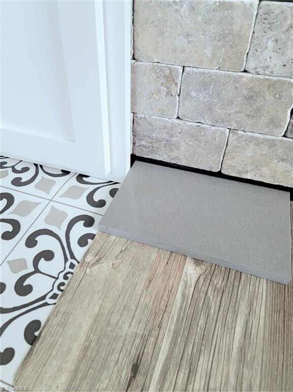 Alpine cabinets, stone tile backsplash, grey quartz counter, grey-brown wood look vinyl in Great and Kitchen, medallion tile look vinyl in Baths
