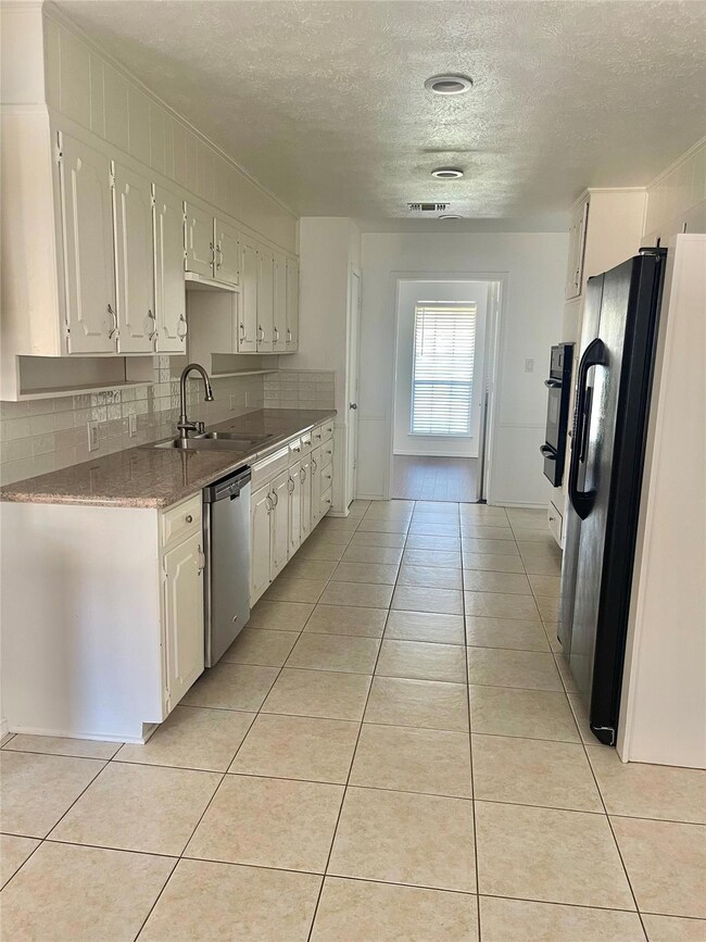 Kitchen with a sink, black appliances, light tile 