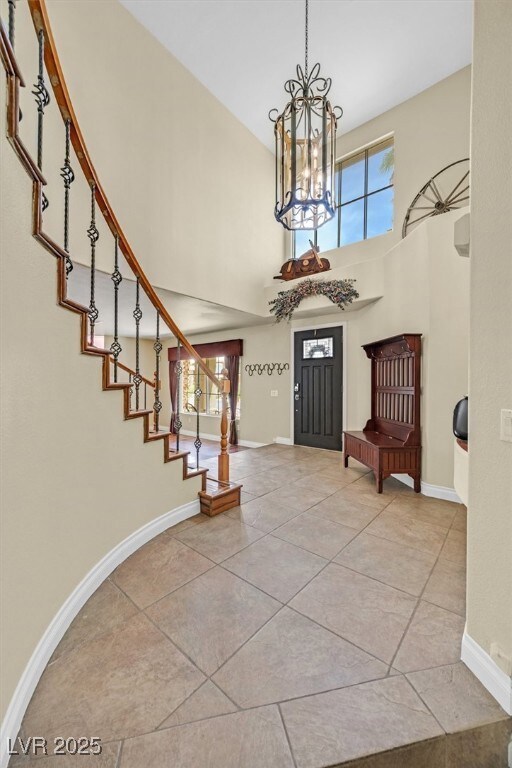 Tiled foyer featuring a towering ceiling, a chande