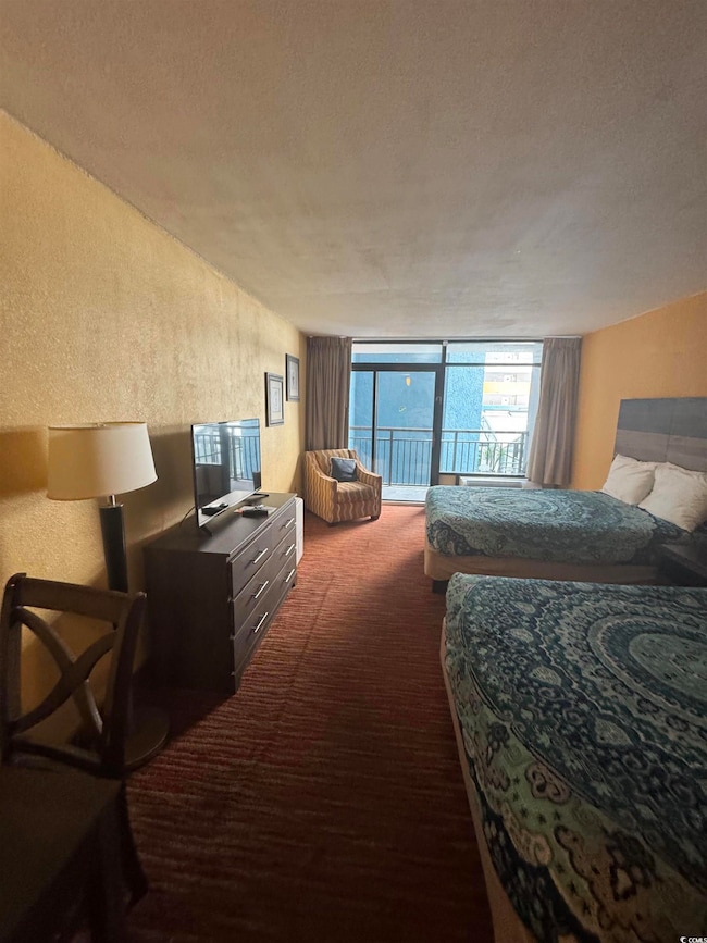 Bedroom featuring a textured wall, a textured ceiling, dark carpet, and access to outside