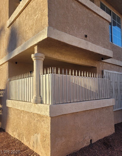 View of side of home with stucco siding and fence