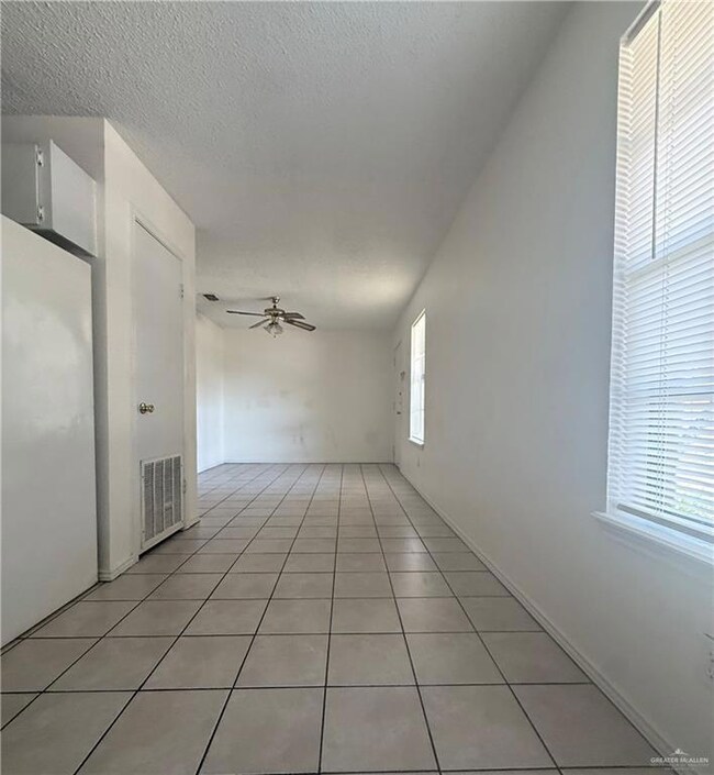 Empty room featuring a ceiling fan, a textured ceiling, and light tile patterned floors
