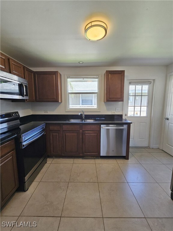 Kitchen featuring stainless steel appliances, dark countertops, and light tile patterned floors