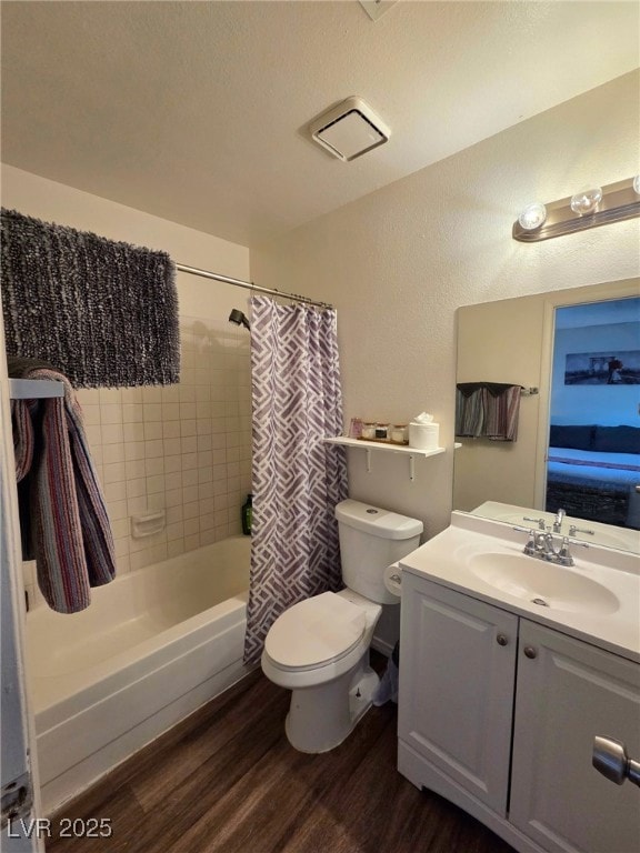 Ensuite bathroom with dark wood-style flooring, vanity, shower / bathtub combination with curtain, and a textured wall