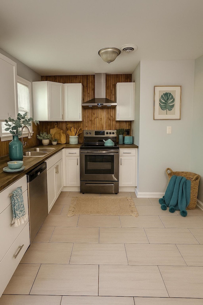 Kitchen with wall chimney exhaust hood, appliances with stainless steel finishes, a sink, and white cabinets