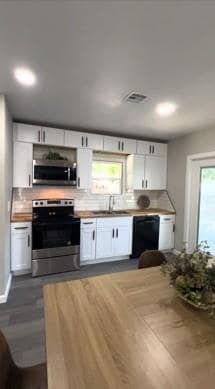 Kitchen featuring stainless steel appliances, backsplash, white cabinetry, and dark wood-style floors