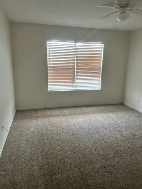 Unfurnished room featuring carpet flooring, a ceiling fan, and baseboards