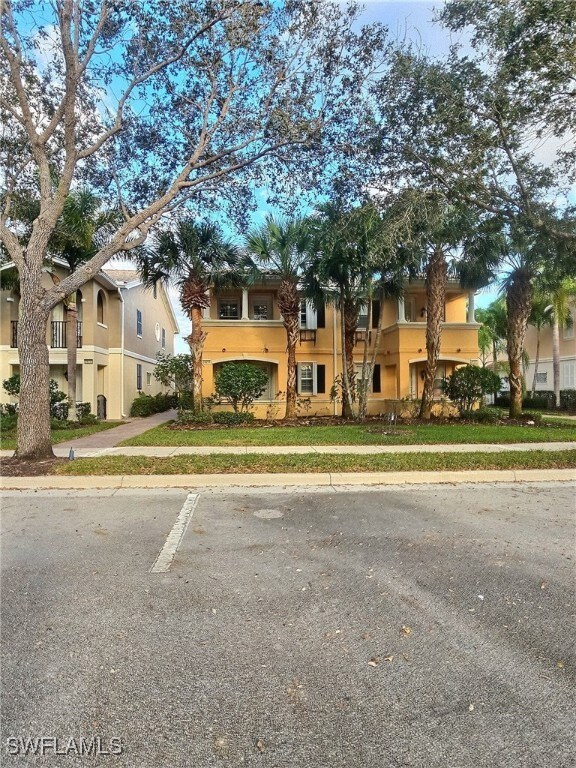 View of front of house with a balcony and a front lawn