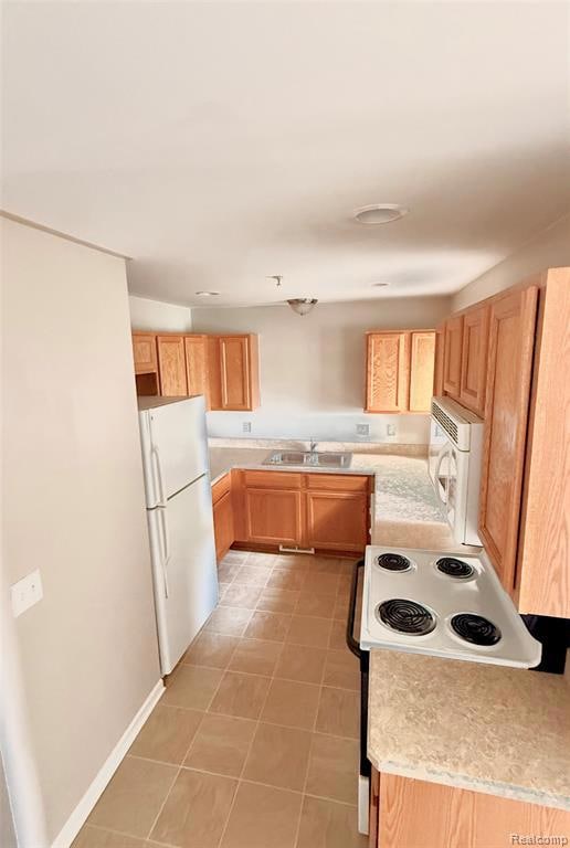 Kitchen featuring light countertops, white appliances, light brown cabinets, and light tile patterned floors
