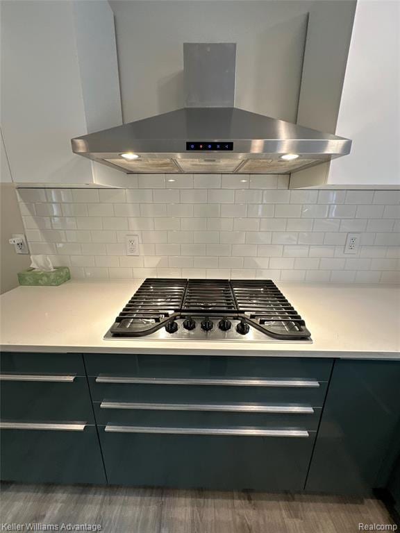 Kitchen with extractor fan, a warming drawer, stainless steel gas cooktop, decorative backsplash, and light stone countertops