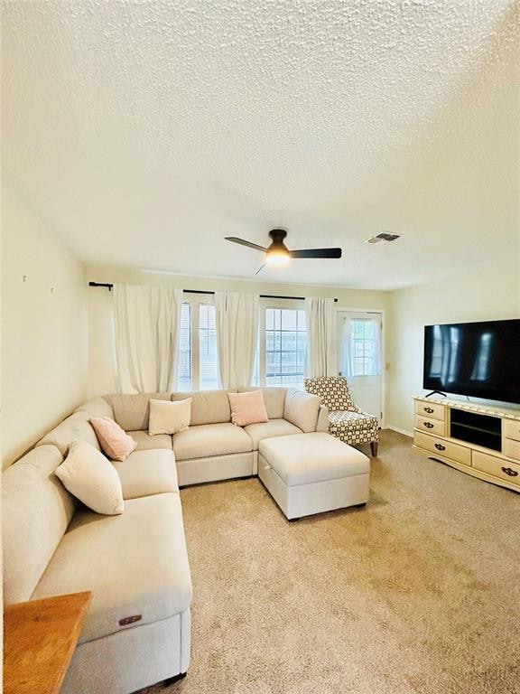 Carpeted living area featuring a ceiling fan