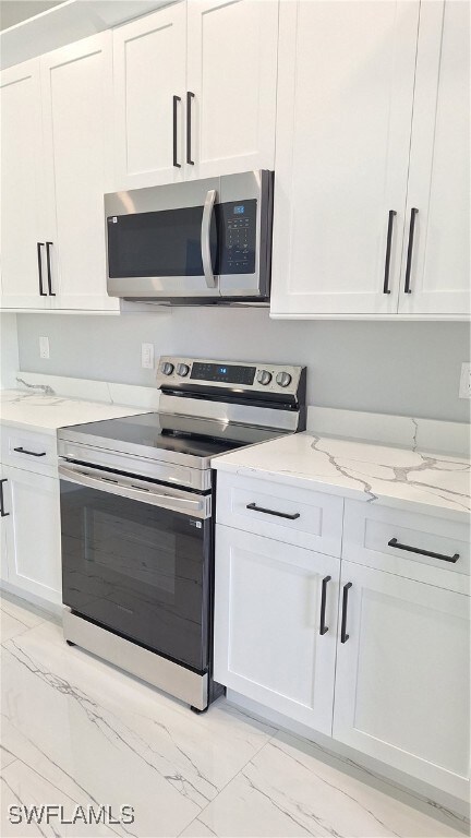 Kitchen featuring electric range, light marble fin