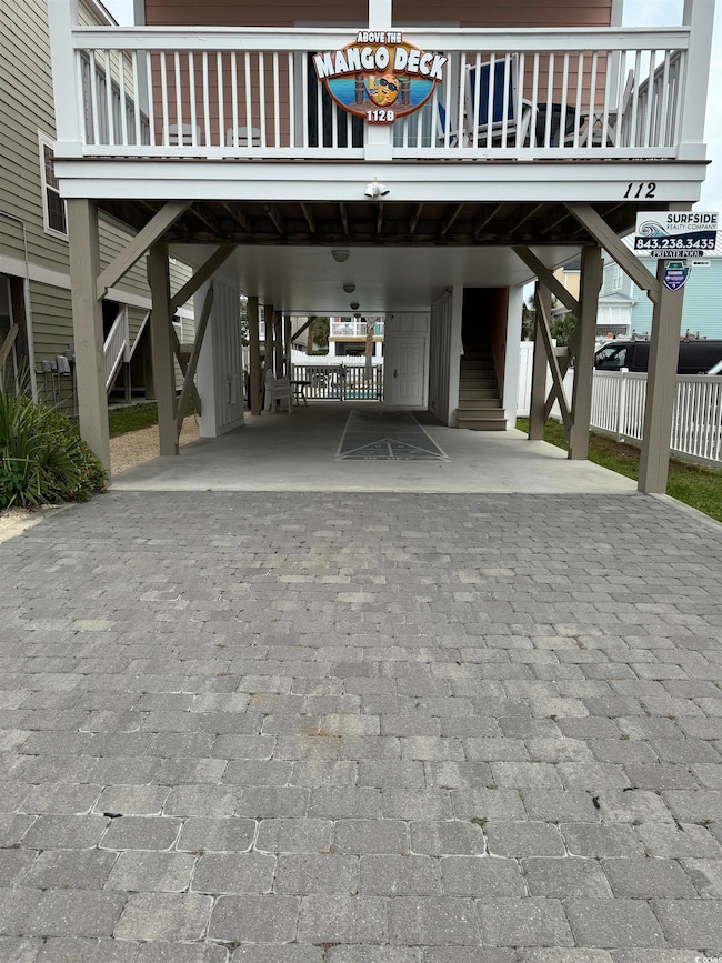 View of parking / parking lot with a carport, stai