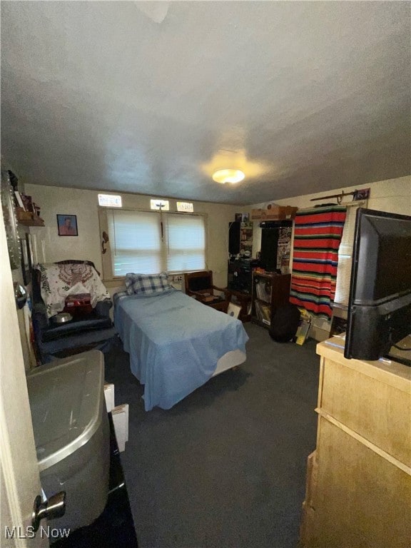 Bedroom featuring dark carpet and a textured ceiling