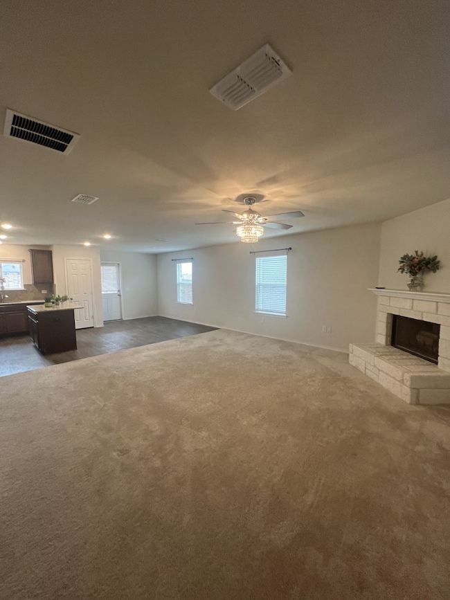Unfurnished living room featuring a fireplace with raised hearth, healthy amount of natural light, and light colored carpet