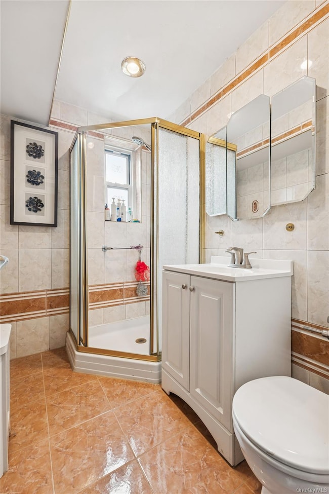 Bathroom featuring tile walls, vanity, and a stall shower
