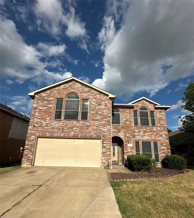 View of property with a garage and a front lawn