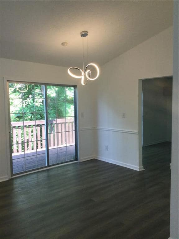 Spare room featuring dark wood-style floors and a chandelier