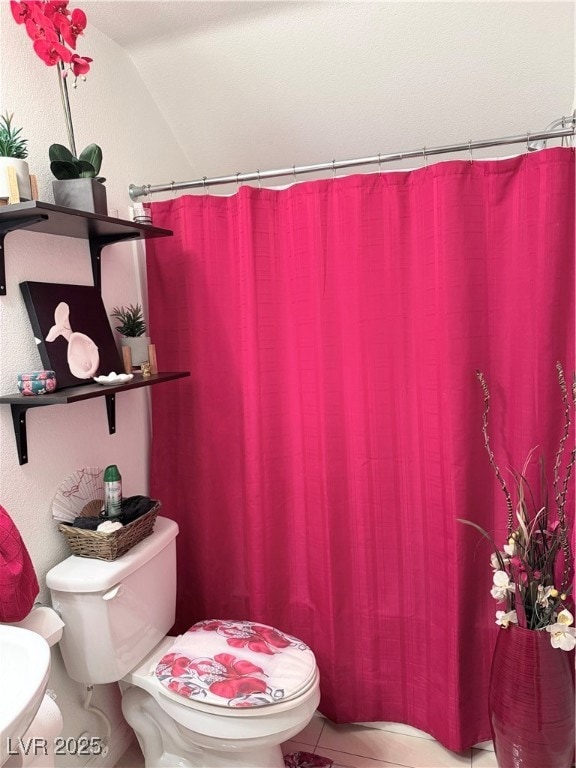 Bathroom with curtained shower and tile patterned floors