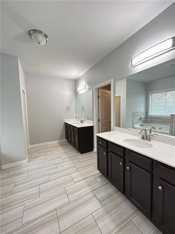 Full bath featuring two vanities, a tub to relax in, and wood finish floors