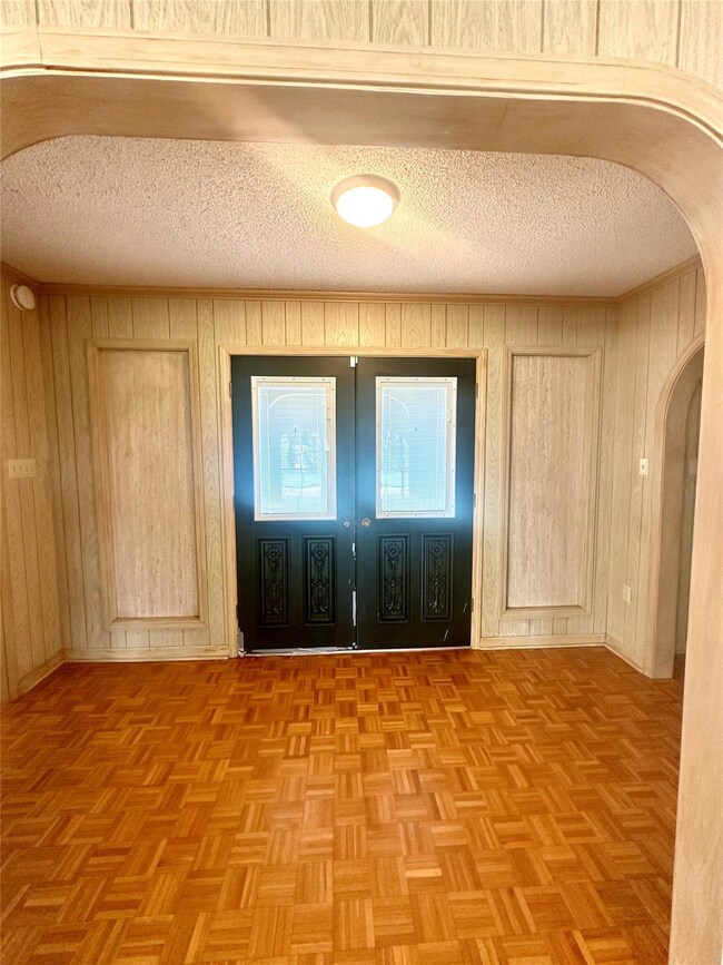 Empty room with light parquet floors, a textured c