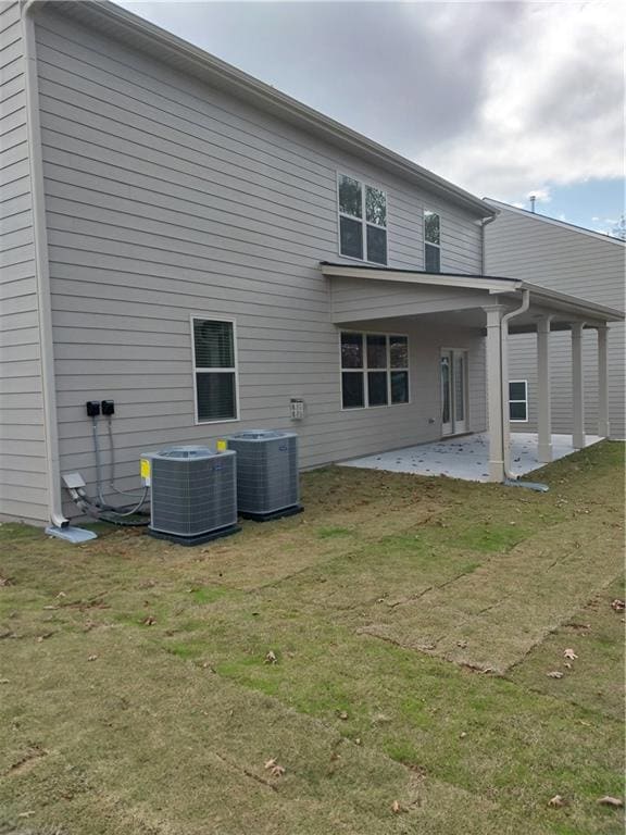 Rear view of house with a yard, central AC, and a 