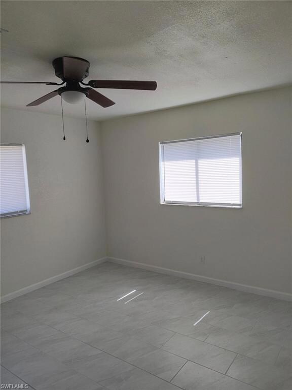Unfurnished room with a ceiling fan and a textured ceiling