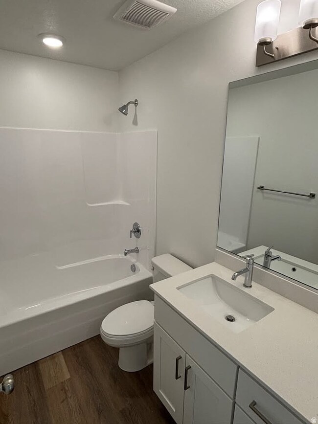 Full bath with vanity, shower / washtub combination, dark wood-style flooring, and a textured ceiling