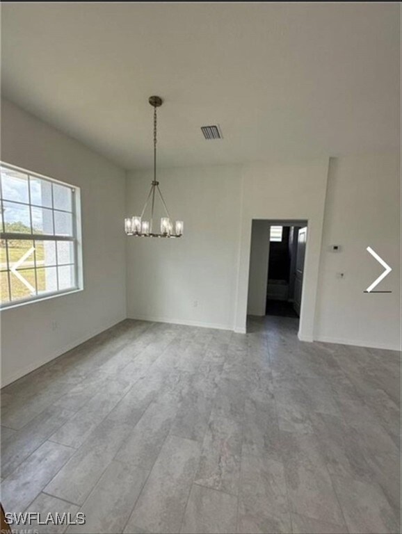 Unfurnished dining area featuring a chandelier and baseboards