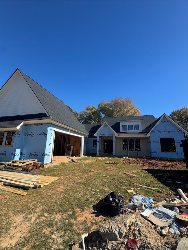 Rear view of property with a lawn and roof with shingles