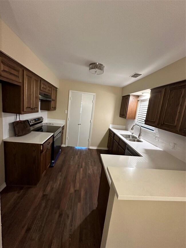 Kitchen with ventilation hood, stove, and dark brown cabinetry