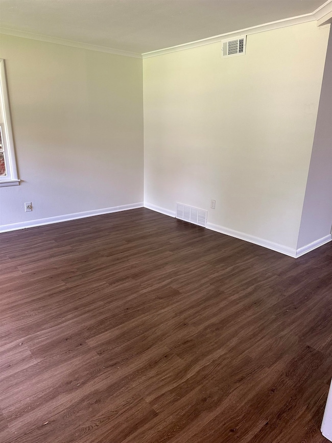 Unfurnished room featuring ornamental molding and dark wood-style floors