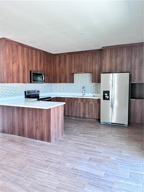 Kitchen featuring fridge, a peninsula, modern cabinets, stove, and light stone counters
