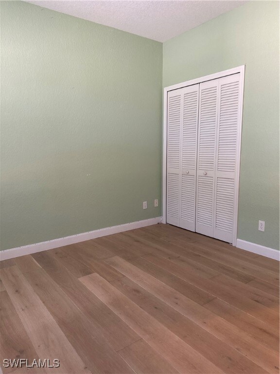 Unfurnished bedroom featuring a textured ceiling, hardwood / wood-style flooring, and a closet