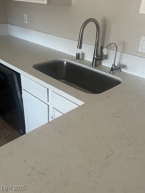 Kitchen view of a sink, white cabinetry, and dishw