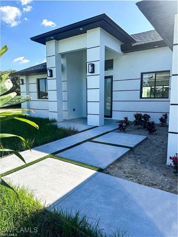 Property entrance featuring stucco siding and a sh
