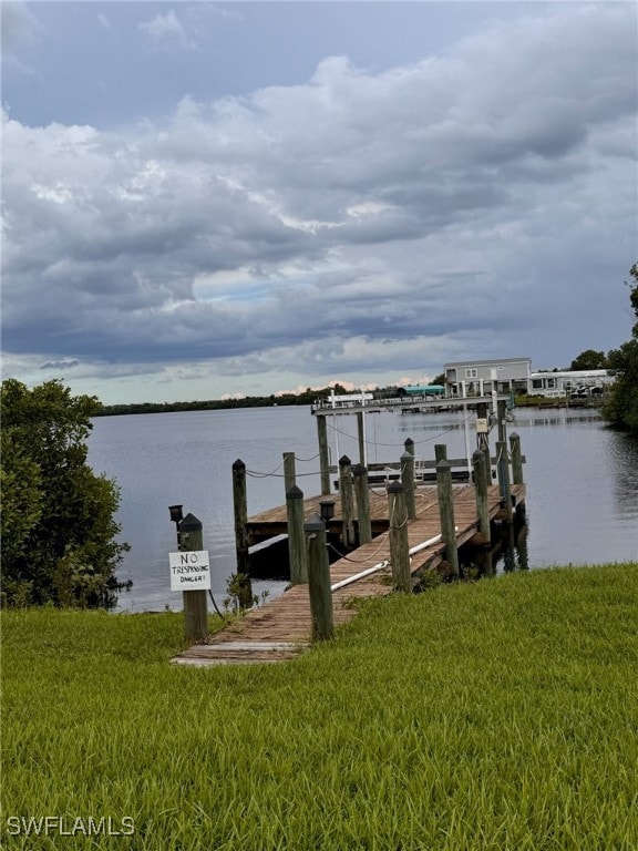 View of dock featuring a water view and a lawn