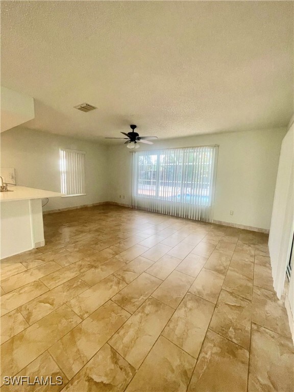 Empty room with ceiling fan and a textured ceiling
