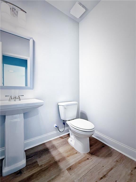 Half bathroom with baseboards, wood finished floor