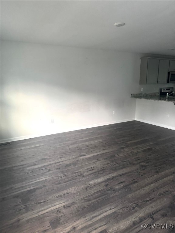 Unfurnished living room featuring dark wood-type f