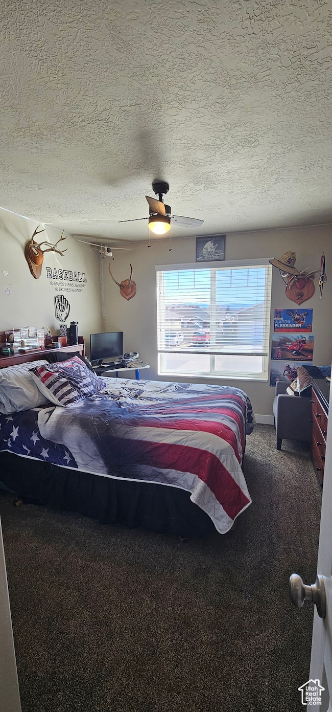 Carpeted bedroom featuring a textured ceiling and a ceiling fan